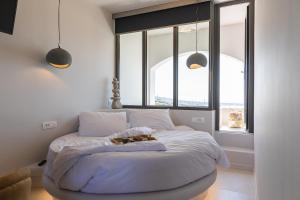 a bed in a bedroom with two windows at Niabelon Suites - Private Jacuzzi Sunset View in Oia