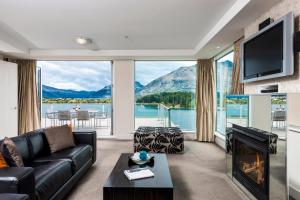 a living room with a fireplace and a view of a lake at Oaks Queenstown Club Suites in Queenstown