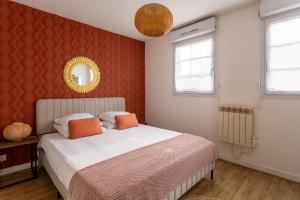 a bedroom with a bed with orange pillows and a mirror at Happy Stay Disney Two - Apartment with garden & parking in Montévrain