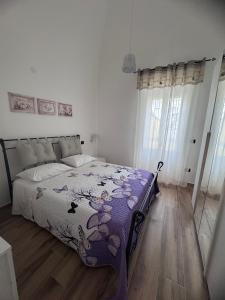 una camera da letto con un letto con un piumone viola di La Casa sul Corso a Talsano
