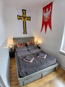 a bedroom with a bed with a cross on the wall at Apartamenty Zakonne "Apartament Rycerza" in Malbork