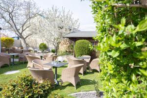 a row of tables and chairs in a garden at Das Reinisch Hotel - near Vienna Airport in Schwechat