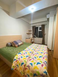 a bedroom with a bed with a colorful comforter at Easton Park Apartment By DPS in Sayang