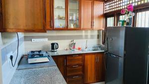 a kitchen with wooden cabinets and a black refrigerator at catherine villa in Ja-Ela +4 photos