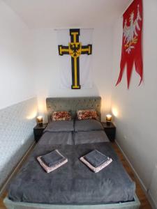 a room with a bed with a cross on the wall at Apartamenty Zakonne "Apartament Rycerza" in Malbork