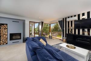 a living room with a blue couch and a fireplace at Villa Andante Malinska in Malinska
