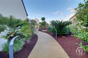 a walkway through a garden with palm trees and plants at Le spa de la palmeraie in Penvénan