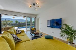 a living room with a yellow couch and a large window at Villa Marina in Kršan