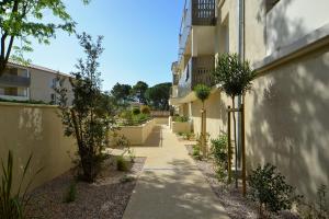a walkway between two buildings with trees and a building at Appartement Uzès, piscine, climatisation, parking privé in Uzès