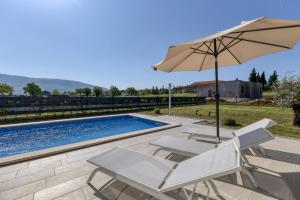a pool with two chairs and an umbrella at Villa Marina in Kršan