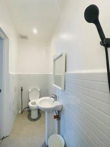 a white bathroom with a toilet and a sink at Private Beach Villa in Zambales in Sampong