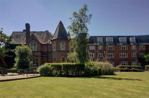 a large brick building with a tree in the yard at Best Western Abbots Barton Hotel in Canterbury