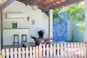 Casasveraneio casa top com 3 suítes com ar condicionado a 100 m da Praia - Barra de São Miguel, 7 minutos do gunga e 3 da praia bonita e conchas ! Área gourmet com piscina privativa e churrasqueira! condomínio com muito verde e piscina de 10m! في بارا دي ساو ميجيل: فناء مع طاولة وكراسي وجدار أزرق وأبيض