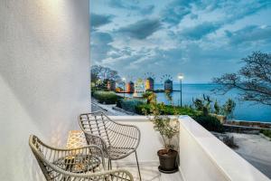 a balcony with two chairs and a view of the ocean at Windmill Escape Apartments A in Chios