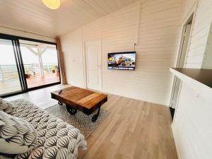 a living room with a table and a tv on the wall at La Kaz Bon'R in Étang-Salé