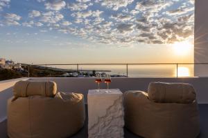a balcony with two chairs and a table with wine glasses at Niabelon Suites - Private Jacuzzi Sunset View in Oia +85 photos