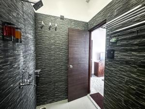 a bathroom with a shower with a wooden door at Bageecha inn in Dehradun