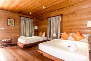 twee bedden in een kamer met houten wanden bij Angkor Heart Bungalow in Siem Reap