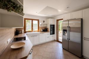 une cuisine avec des armoires blanches et un réfrigérateur en acier inoxydable dans l'établissement Traumhafte Finca am Es Trenc, à Ses Covetes