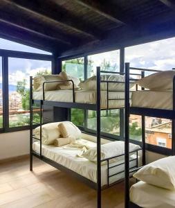 two bunk beds in a room with a large window at Lazy Roo Hostel Saranda in Sarandë