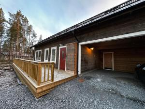 a house with a large deck next to a building at Modern Mountain Cabin in Idre 1022 in Idre