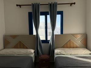 two beds in a room with a window at Marassi in Dawwār Abū Maḩrūs