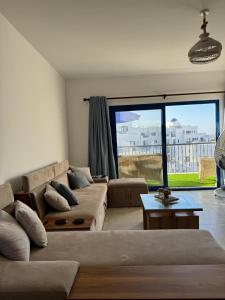 ein Wohnzimmer mit Couch und großem Fenster in der Unterkunft Marassi in Dawwār Abū Maḩrūs