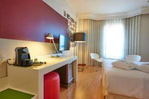 a hotel room with a bed and a desk with a television at Hotel Vigo Los Galeones Affiliated by Meliá in Vigo