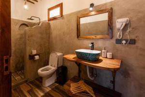 a bathroom with a sink and a toilet and a mirror at Ananda Beach Hotel in Paje