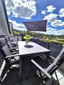 una mesa blanca y sillas en un balcón con sombrilla en Winterberg Appartement 21136, en Winterberg