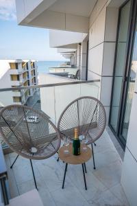 2 sillas y una mesa con una botella de vino en el balcón en Dream luxury apartments in Infinity pool Spa resort, en Mamaia