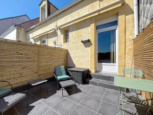 een patio met stoelen, een bank en een hek bij Le Mourillon - Centre Ville in Wimereux