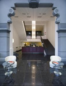 un gran vestíbulo con 2 sillas y una escalera en Italiana Hotels Milan Rho Fair, en Rho