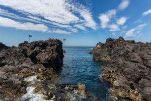 a group of people swimming in the ocean between rocks at Quinta do Atlântico in Biscoitos