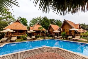 a resort pool with chairs and umbrellas at Angkor Heart Bungalow in Siem Reap