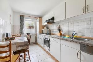 a kitchen with white cabinets and a sink and a table at Ferienhof Martens in Schülperweide