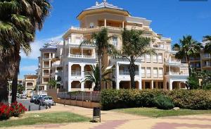 a large white building with palm trees in front of it at Atlántico, Playa Punta del Moral - By AC REAL in Punta del moral