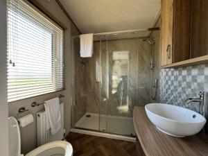 une salle de bain avec une baignoire, des toilettes et une douche dans l'établissement Stewarts Resort Lodge 59, à St Andrews 18 autres photos