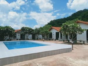 a swimming pool in front of a house with trees at เขาแคบ วิลล่า in Pak Chong