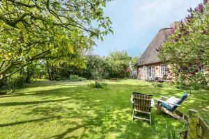 a garden with a bench and a thatched house at Das Deichhaus in Norddeich