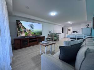a living room with a couch and a flat screen tv at The Love Shack in Bongaree