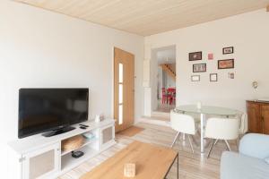 a living room with a flat screen tv and a table at Maison aux Moutiers - Wifi - Terrasse in Prigny