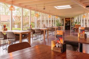 a restaurant with tables and chairs and windows at Landhotel Diever in Diever