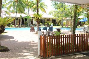 a fence next to a pool with a table and chairs at Langkah Syabas Beach Resort in Kinarut