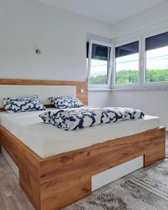 a bedroom with a large wooden bed with blue and white pillows at Villa Vienna in Bužim