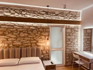 a bedroom with a stone wall with a bed and a sink at SARANDA Vila HM in Sarandë