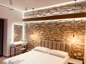 a bedroom with a bed and a stone wall at SARANDA Vila HM in Sarandë