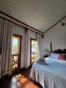 a bedroom with a large bed and a window at Pousada Padre Toledo in Tiradentes
