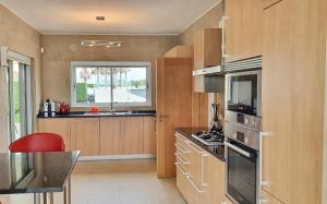 Una cocina con gabinetes de madera y una silla roja. en Fantástica V3 Vista Mar & Golfe Praia Del Rey, Óbidos, en Amoreira
