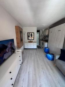 ル・ラヴァンドゥーにあるAPPARTEMENT ET SA JOLIE TERRASSE Le Lavandou Saint Clair, a deux pas de la plage de St Clair, au calme, Studio tout équipé, clim, Wifi Fibre, TV connectée, lave linge, lave vaisselle, place de parking et plus, serviettes et draps fournisのソファとテレビのあるリビングルーム
